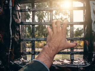 Man hand on iron grate. Criminal in captivity or imprisonment concept.