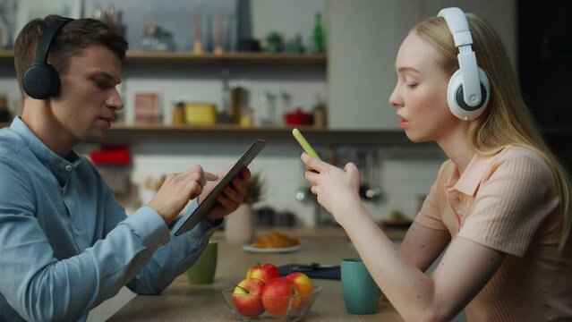 Couple ignoring communication addicted to gadgets close up. Pair listening music