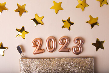 Open golden cosmetic bag with shiny gold stars around.Rose gold numbers 2023 above.Concept of the...