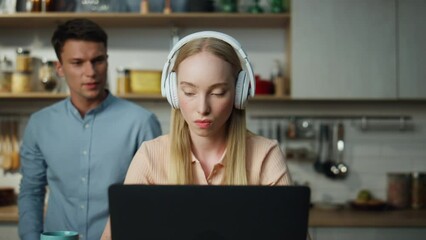 Business woman working home on laptop with headset man trying distract closeup