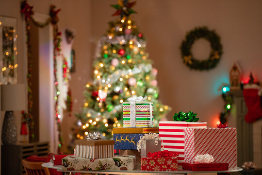 Christmas Gifts Stacked On A Table In Front Of A Christmas Tree In A Family Room. 