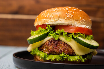 Burger in bun with beef meat and cheese, served on black plate