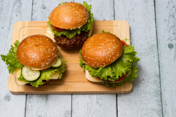 Delicious burgers with lettuce and cheese served on cutting board