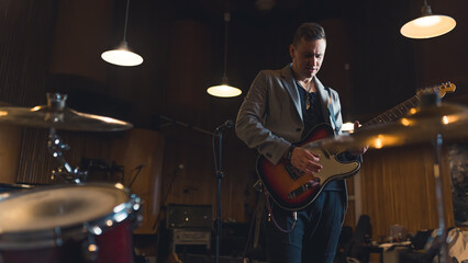 Man playing electric guitar in a studio around musical instruments and equipment. High quality photo