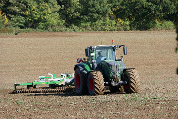 Fototapeta premium Landwirt eggt mit seinem Traktor ein Feld nahe der Sababurg