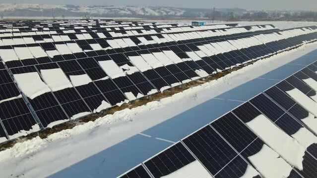 Aerial view of snow melting from covered solar photovoltaic panels at sustainable electric power plant for producing clean electrical energy. Low effectivity of renewable electricity in winter