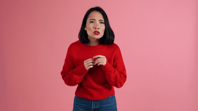 Worried Asian fan woman wearing red sweater getting upset about losing in the pink studio