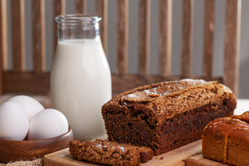 chocolate cupcake on a wooden board, a bottle of milk and eggs on the table. Close-up.