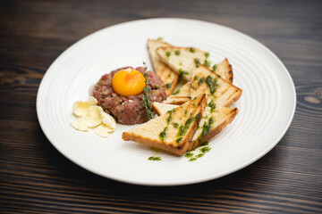 a tasty dish of meat and egg yolk with croutons on a plate.