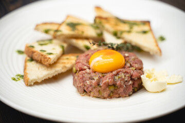 a tasty dish of meat and egg yolk with croutons on a plate.
