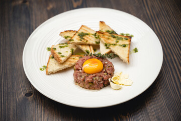 a tasty dish of meat and egg yolk with croutons on a plate.