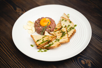 a tasty dish of meat and egg yolk with croutons on a plate.