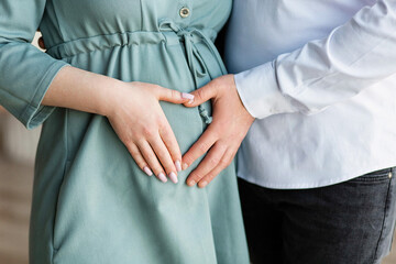 A pregnant woman and a loving husband hugs her stomach on a white background. The feeling of the...