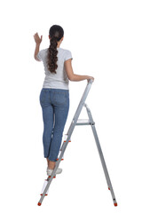 Young woman on metal ladder against white background, back view © New Africa
