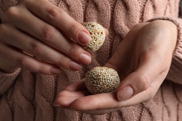 Woman holding delicious vegan candy balls with sesame seeds, closeup