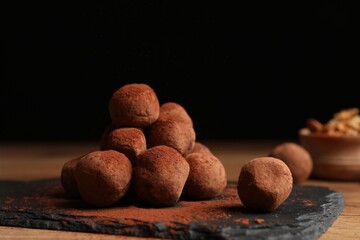 Tasty chocolate truffles powdered with cacao on slate board