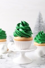 Delicious cupcakes with green cream and Christmas decor on white marble table