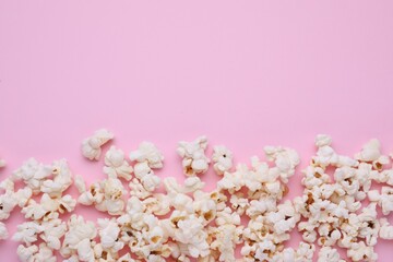 Obraz na płótnie Canvas Tasty popcorn scattered on pink background, flat lay. Space for text