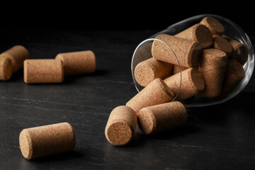 Glass with wine corks on dark table, closeup