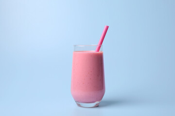 Glass with delicious fresh berry smoothie on light blue background