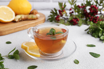 Glass cup of delicious immunity boosting tea with ingredients on light grey table