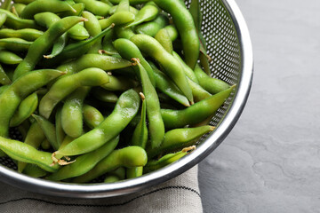 Sieve with green edamame beans in pods on table, closeup
