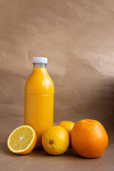 still life - a plastic bottle with orange juice and three ripe fruits and a cut off half of an orange - close-up