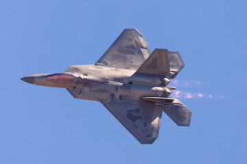 Fototapeta na wymiar F-22 Raptor in a turn in beautiful light , with afterburners on