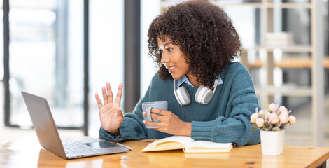 Cute african american female student wearing headphones with afro dreadlocks, studying remotely...