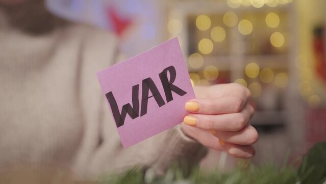 A woman burns a sheet with the word war with a Christmas background. Video about mental problems during the war.