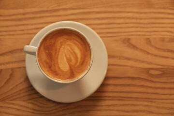 Cup of hot coffee on wooden table, top view. Space for text