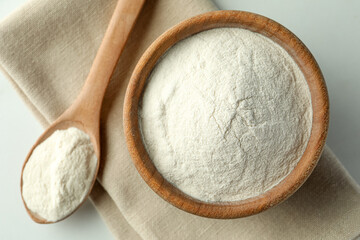 Bowl and spoon of agar-agar powder on white table, top view