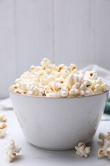 Bowl of tasty popcorn on white table, closeup