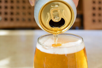 Pouring beer from can into glass on table, closeup