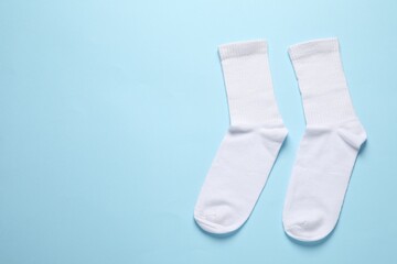 Pair of white socks on light blue background, flat lay. Space for text
