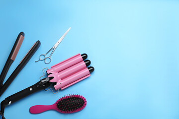 Flat lay composition of professional hairdresser tools on light blue background, space for text