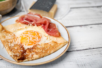 Delicious crepe with egg on white wooden table, closeup. Breton galette - obrazy, fototapety, plakaty