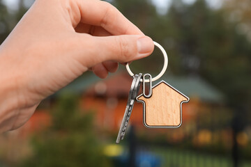 Woman holding house keys outdoors, closeup. Real estate agent