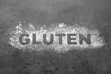 Word Gluten written with flour on grey background, top view