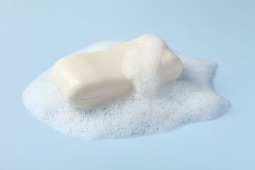 Soap with fluffy foam on light blue background