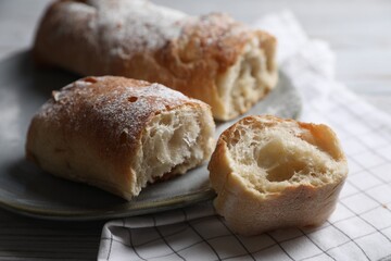 Fresh crispy ciabattas on white wooden table, closeup