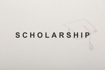 Word SCHOLARSHIP and academic cap on white paper