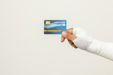 Closeup man broken arm holding credit card payment. Man put on plaster bandage cast splint. Male...