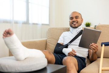 Happy man recovery from accident fracture broken bone injury with leg splints in cast neck splints...