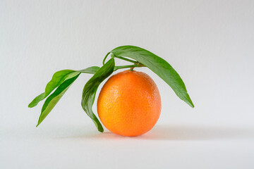 Tangerine with green leaves on the background of a white paper