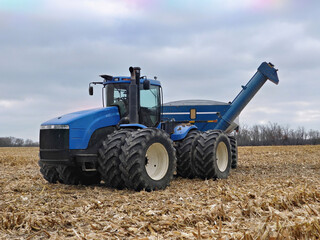 large tractor pulling a grain cart in a harvested corn field