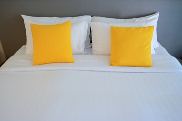 Fototapeta na wymiar yellow pillow on white bed, interior design