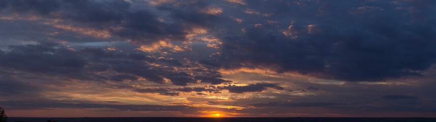 Landscape with bloody sunset. Panorama. Tragic gloomy sky. The last flashes of the sun on the storm clouds.