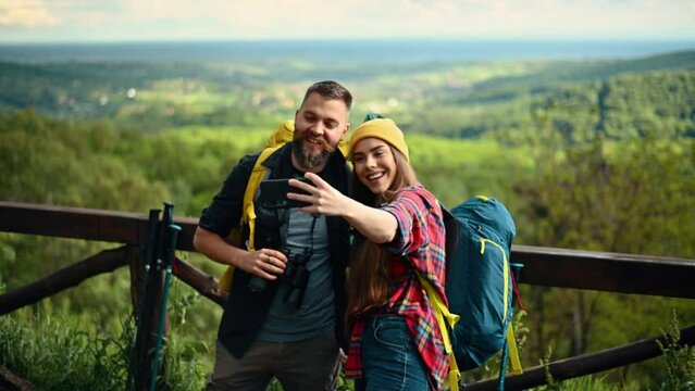 Couple of hikers taking selfie with a smartphone while at the lookout in the nature