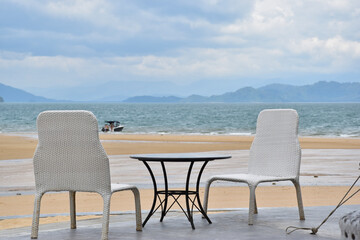 Fototapeta na wymiar White woven chairs for eating snacks and taking in the sea breeze.